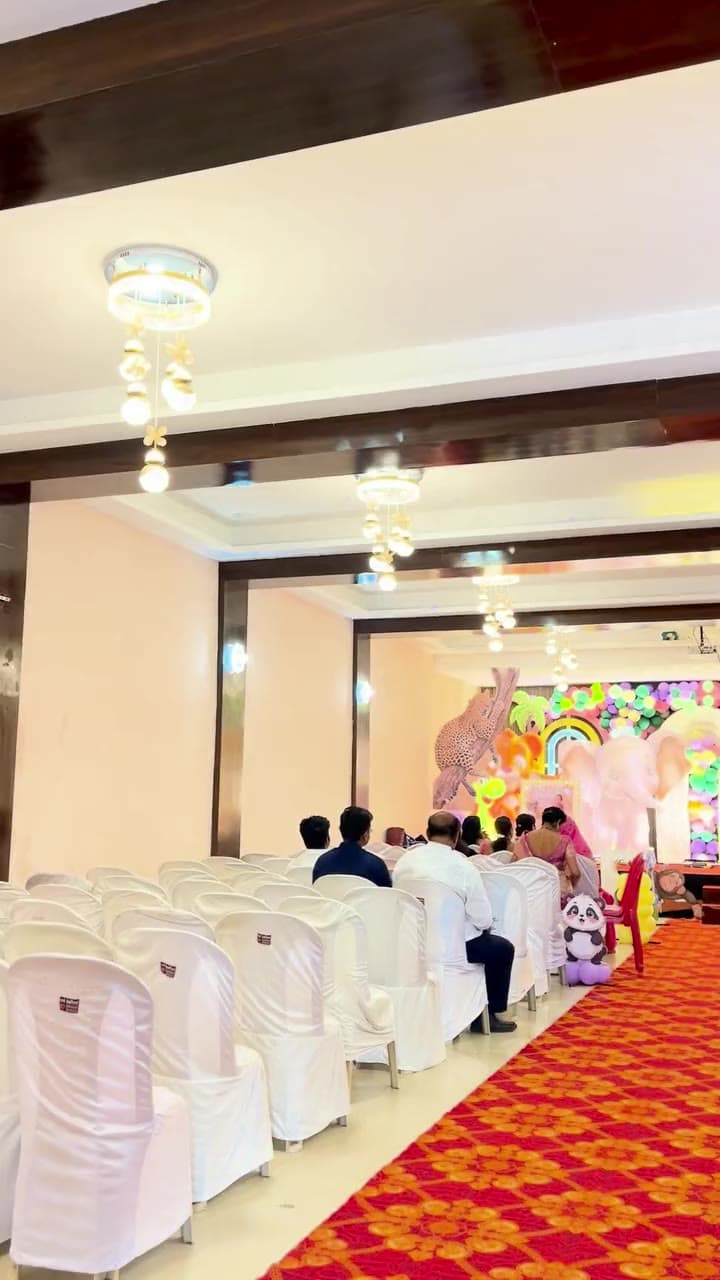 The AC banquet hall at Sai Samrat with chandeliers and covered chairs